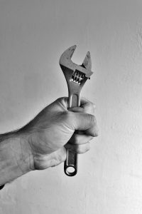 Close-up of a hand gripping an adjustable wrench in classic black and white style.